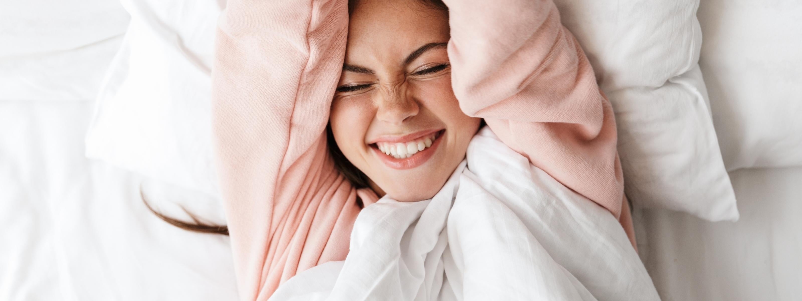 Woman enjoying soft white organic cotton bedding by AnAká for a cozy and comfortable sleep experience