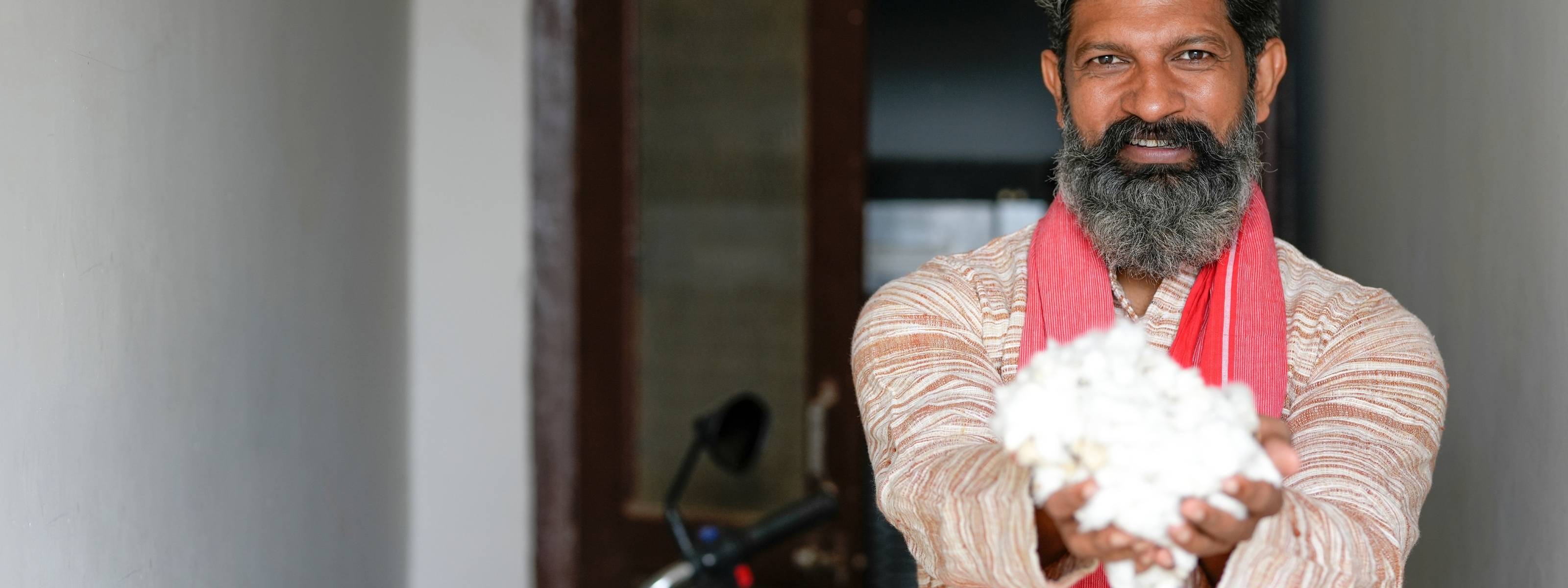 Indian organic cotton farmer holding freshly harvested cotton for AnAká sustainable luxury bedding and organic cotton bedsheets production