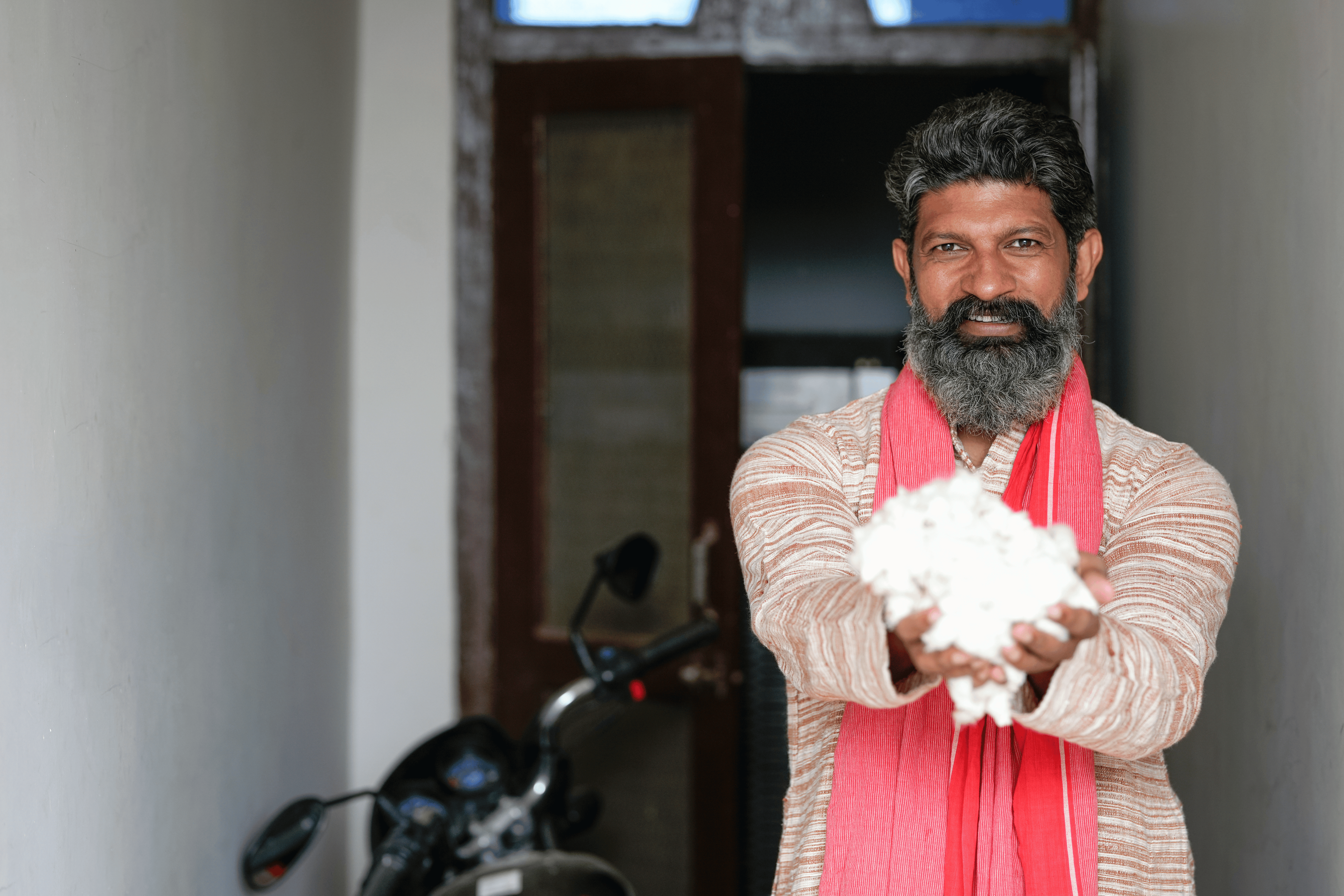Indian farmer holding freshly harvested organic cotton in a field, representing sustainable and natural bedding materials for Anaka